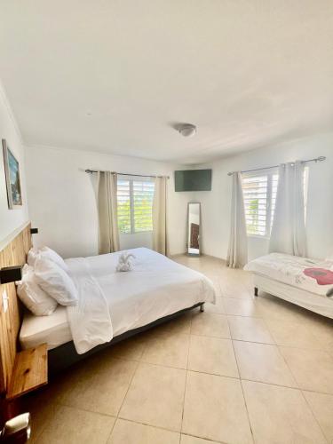 a bedroom with a large white bed and two windows at Nos Yemaya, 2BR, Pool, walking distance from Playa Lagun in Lagun