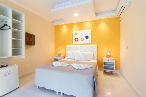 a bedroom with a white bed and a yellow wall at Villa Araçà - Boutique Hotel in Lauro de Freitas