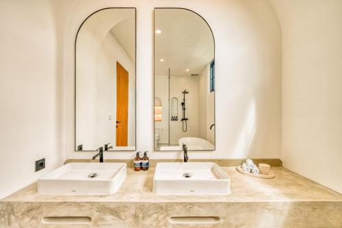 two sinks in a bathroom with two mirrors at Senada Garden in Uluwatu