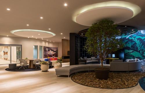 a lobby with couches and a tree in the middle at Novotel RJ Praia de Botafogo in Rio de Janeiro