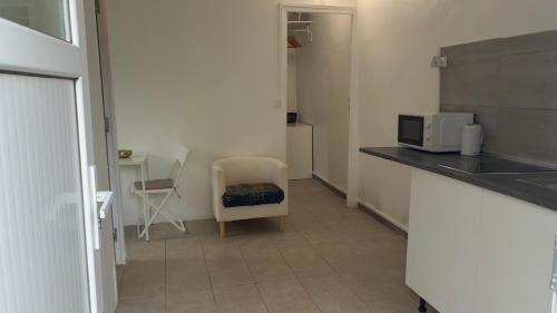 a kitchen with a counter and a chair and a microwave at Le Nid Chaleureux Ecoresponsable in Sevran