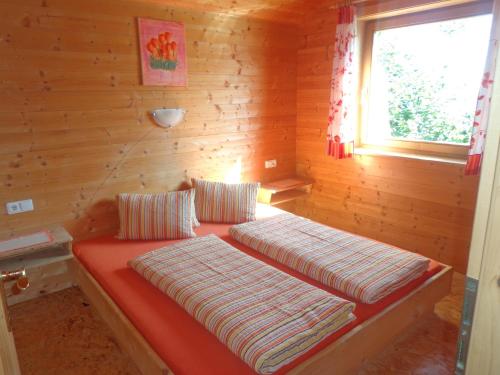 two beds in a log cabin with a window at Ferienhütte Georg in Hippach