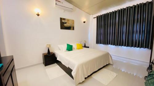 a white bedroom with a bed and a window at Erin Orr Villa in Wadduwa