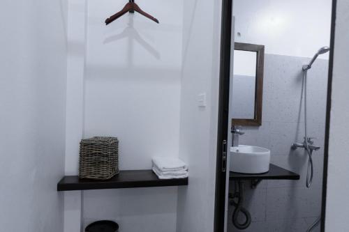 Un baño blanco con lavabo y espejo. en Anio Ha Giang Hotel, en Ha Giang