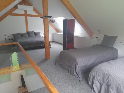 a attic bedroom with two beds and a glass table at Kromven in Merksplas