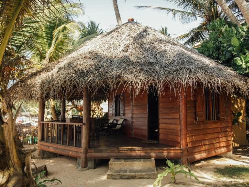 a small hut with a thatched roof on the beach at Galawatta Beach Resort in Unawatuna