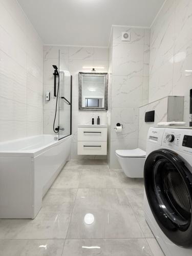 a white bathroom with a washing machine in it at Apartament Natura in Piła