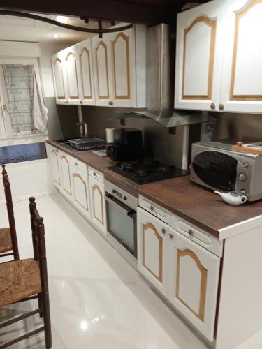 una cucina con mobili bianchi e un forno con piano cottura di La CATALANE ad Argelès-sur-Mer
