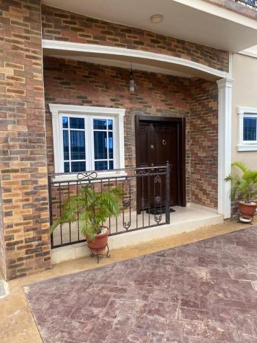 Un balcón de un edificio de ladrillo con dos plantas en macetas. en Beautiful 2 beds with self compound and private parking space, en Iju Junction