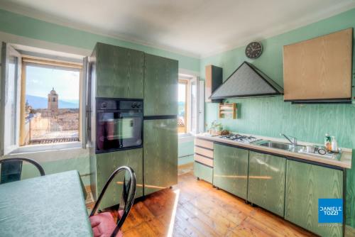 a kitchen with green cabinets and a view of a city at La Neviera Nel Pozzo in Offida