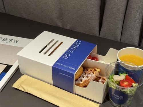 eine Box mit Essen, ein Salat und ein Glas Saft in der Unterkunft Atour Hotel Shanghai Wujiaochang Huangxing Road Subway Station in Shanghai