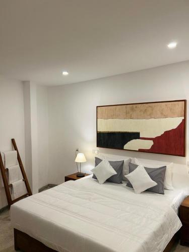 een slaapkamer met een groot wit bed met een schilderij aan de muur bij The Urban Escape in Matara