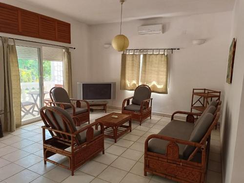 un salon avec des chaises et une télévision à écran plat dans l'établissement Les jardins d'Ambondrona, à Mahajanga
