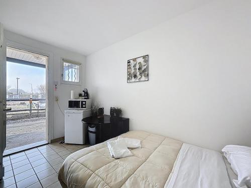 a white bedroom with a bed and a kitchen at Unique Chambre 1 Centre Équestre Snack in Vic-le-Comte