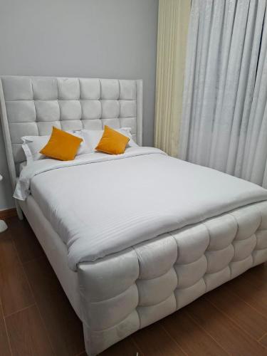 een groot wit bed met 2 gele kussens erop bij Haven Place 254 in Nairobi