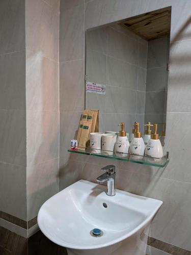 a bathroom with a sink and a mirror with cups at Homely House Bảo Lộc in Ấp Tân Hà
