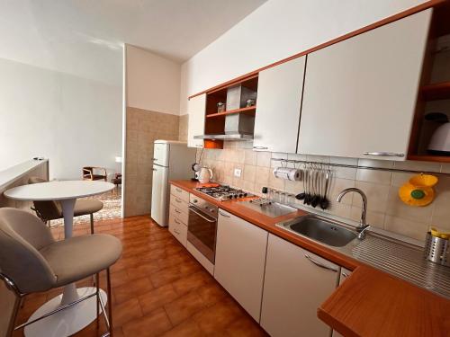 een keuken met witte kasten, een wastafel en een tafel bij Top Stay Retrò in Costa Volpino