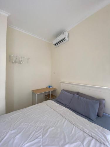 a bedroom with a white bed and a table at Omah Sulaem Homestay in Malang