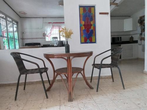 a wooden table with two chairs and a vase on it at Casa jardín nueva gorgona in Nueva Gorgona