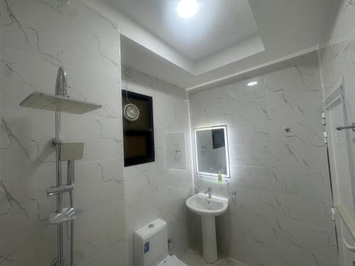 a white bathroom with a sink and a toilet at Faj Residence home stay in Ajman 