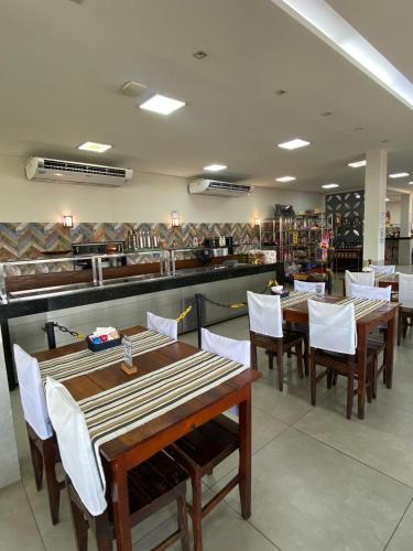 a restaurant with wooden tables and white chairs and a counter at Parada Guanabara in Belo Oriente