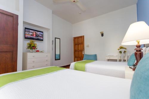 a bedroom with two beds and a tv on the wall at The Liguanea Club in Kingston