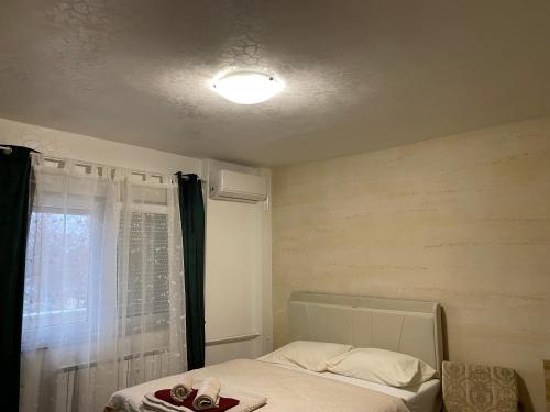 a small bedroom with a bed and a window at BelleVu studio apartman in Vukovar