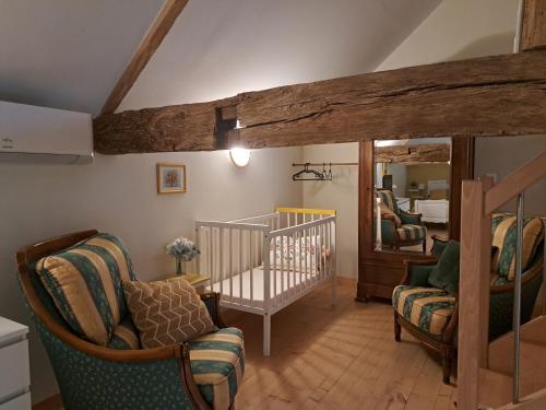 a room with a crib and chairs and a bedroom at La Métairie au milieu des vignes in Réaux