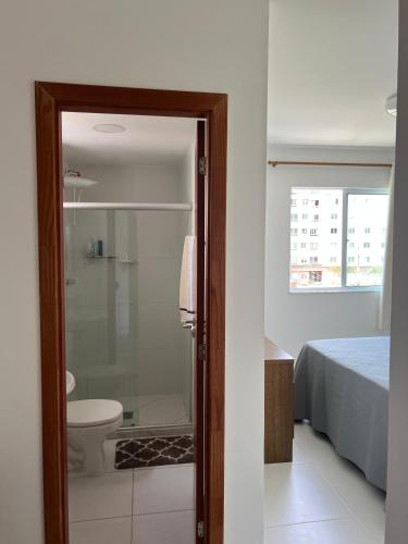 a bathroom with a shower and a toilet and a bed at VOG Torres do Sul Litoral Ilhéus in Ilhéus