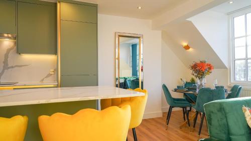 a kitchen and dining room with yellow chairs and a table at NEW Luxurious Stunning Block Apartments in Central London in London