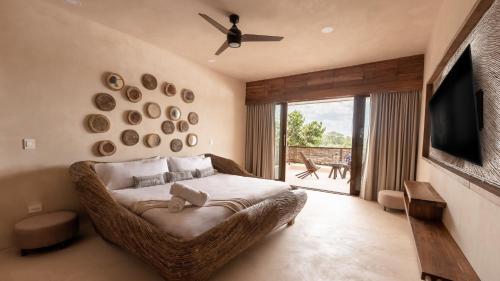 una camera da letto con un letto, una televisione e un balcone di Kuunaa Tulum I Beer Sanctuary & Spa a Tulum