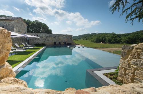 Verfeuil的住宿－Domaine de Gressac，石头建筑前的游泳池