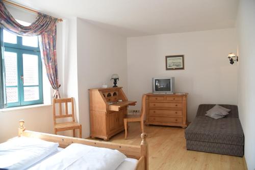 a bedroom with a bed and a desk with a television at Altstadthotel Garni Schlundhaus & Rautenkranz in Meiningen