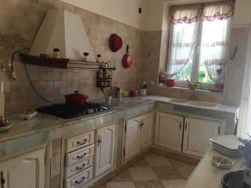 Una cocina con gabinetes blancos, un fregadero y una estufa. en Maison de Sila, en Bir el Djir