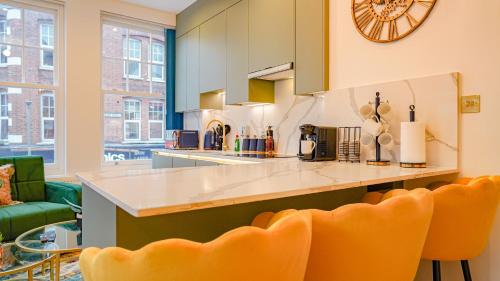 a kitchen with orange chairs and a large clock on the wall at NEW Luxurious Stunning Block Apartments in Central London in London