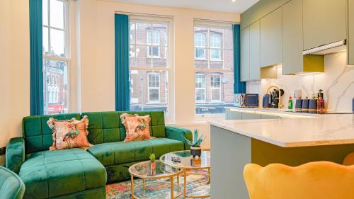a living room with a green couch and a kitchen at NEW Luxurious Stunning Block Apartments in Central London in London