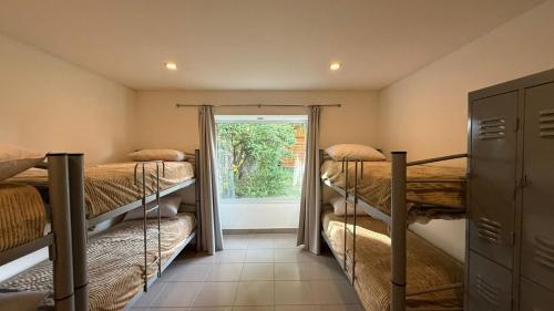 a room with three bunk beds and a window at El Puente - Departamentos Independientes in El Calafate