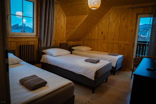 two beds in a room with wooden walls and windows at Nebbia Ressort in Karpacz