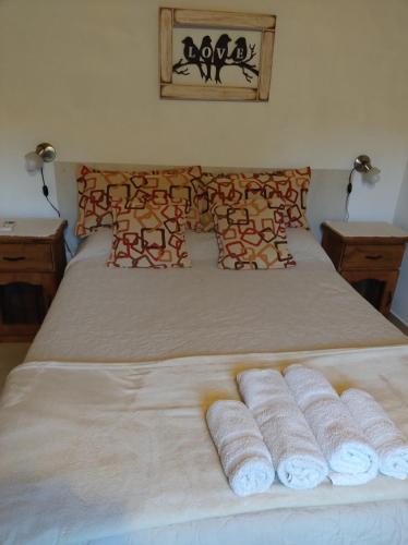 Una cama con cuatro toallas enrolladas. en Cabañas Rincon Verde, en Merlo