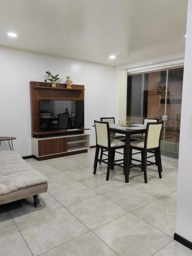 a dining room with a table and chairs and a tv at 2p Departamento en Torres Ventura in Cochabamba