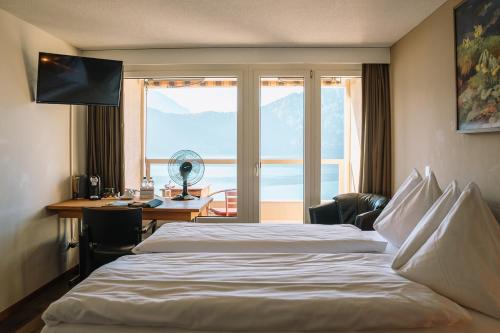 a hotel room with a bed and a desk and a window at Alpenblick Weggis - Panorama & Alpen Chic Hotel in Weggis