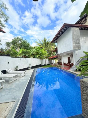 a pool in front of a house with blue water at Pineapple Surf Villa in Ahangama