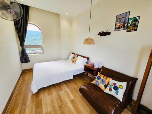 a bedroom with a bed and a couch and a window at Khách Sạn Trung Loan in Ninh Hải
