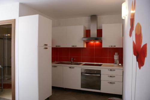a small kitchen with white cabinets and red walls at Apartment Adria Sun in Porat