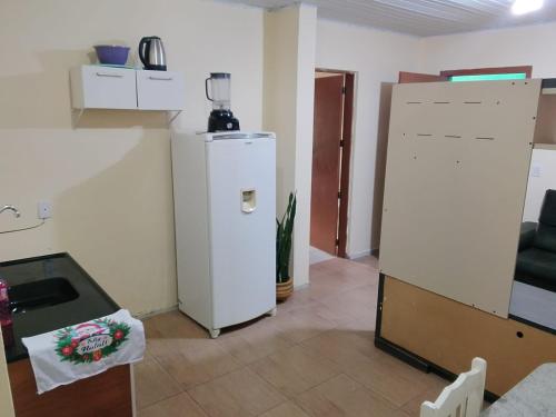 een woonkamer met een koelkast en een tafel bij Kitnet com garagem e Wi-Fi in Tramandaí