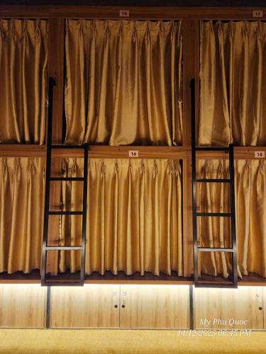 two ladders in a room with brown curtains at Mi Amor Luxury Hostel located in South Island Center in Phú Quốc