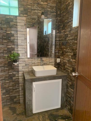 a bathroom with a sink and a stone wall at Menuks villa in Habaraduwa Central