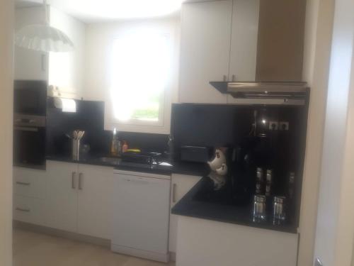 een keuken met witte kasten en een zwart aanrechtblad bij Super Apt terrasse 2box in Olivet