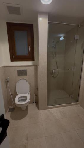 a bathroom with a toilet and a glass shower at Hawana Apartment in Salalah