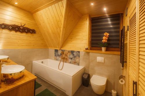 a bathroom with a tub and a toilet and a sink at Villa Alexandra jacuzzi i sauna in Kościelisko
